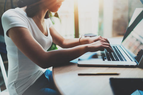 Side profile of a woman sitting at a desk typing on a laptop